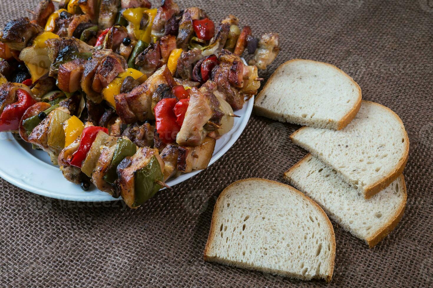 Grilled meat skewers with vegetables and bread photo
