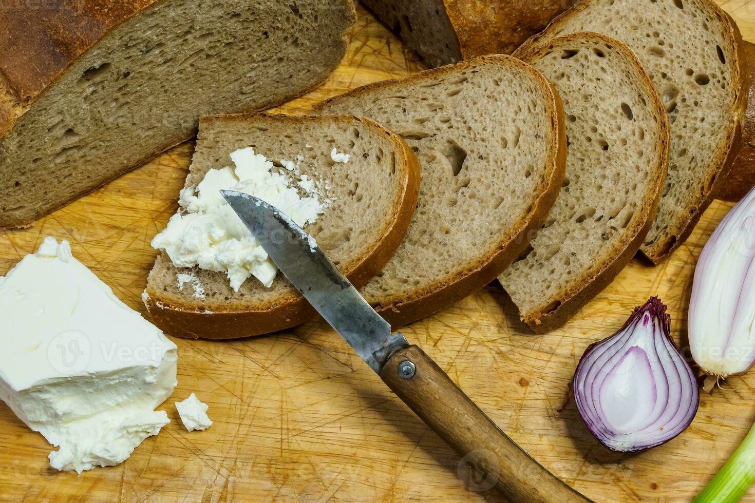hogar hecho un pan en un de madera corte tablero con Cuajada queso. decorado con Fresco verde cebollas o primavera cebollas foto