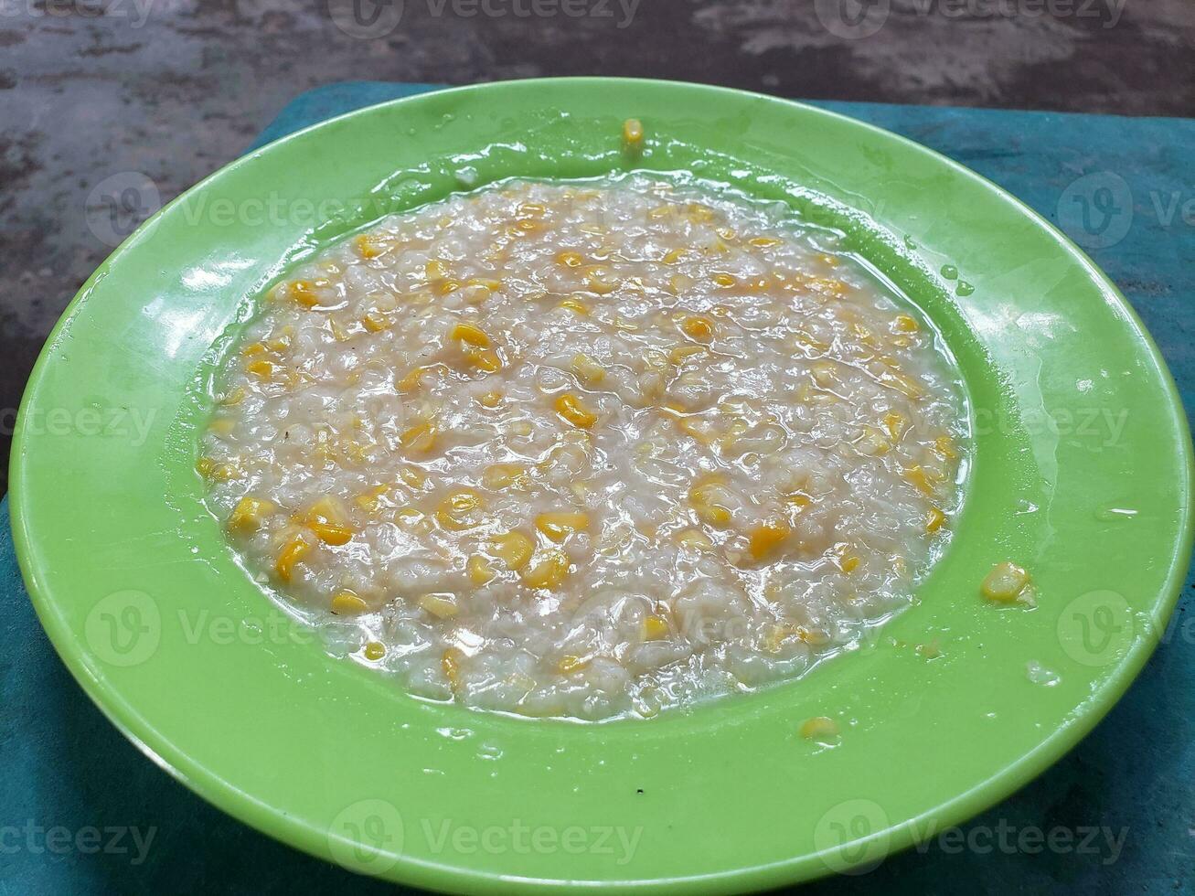 Corn grits in a green plate isolated on table background photo