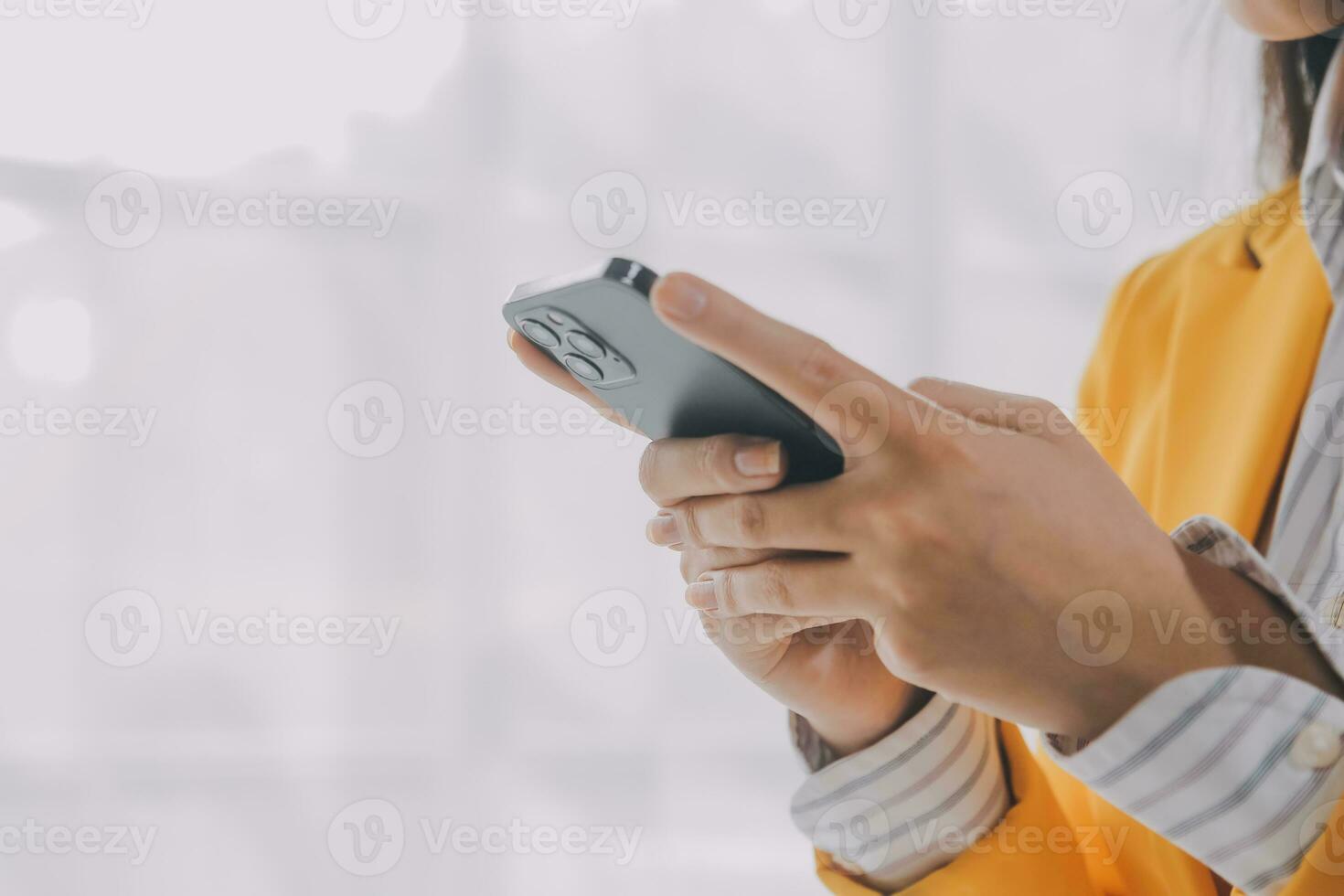 Business woman using mobile phone during working on laptop computer, surfing the internet, searching business data at modern office. Asian businesswoman online working on computer at workplace photo