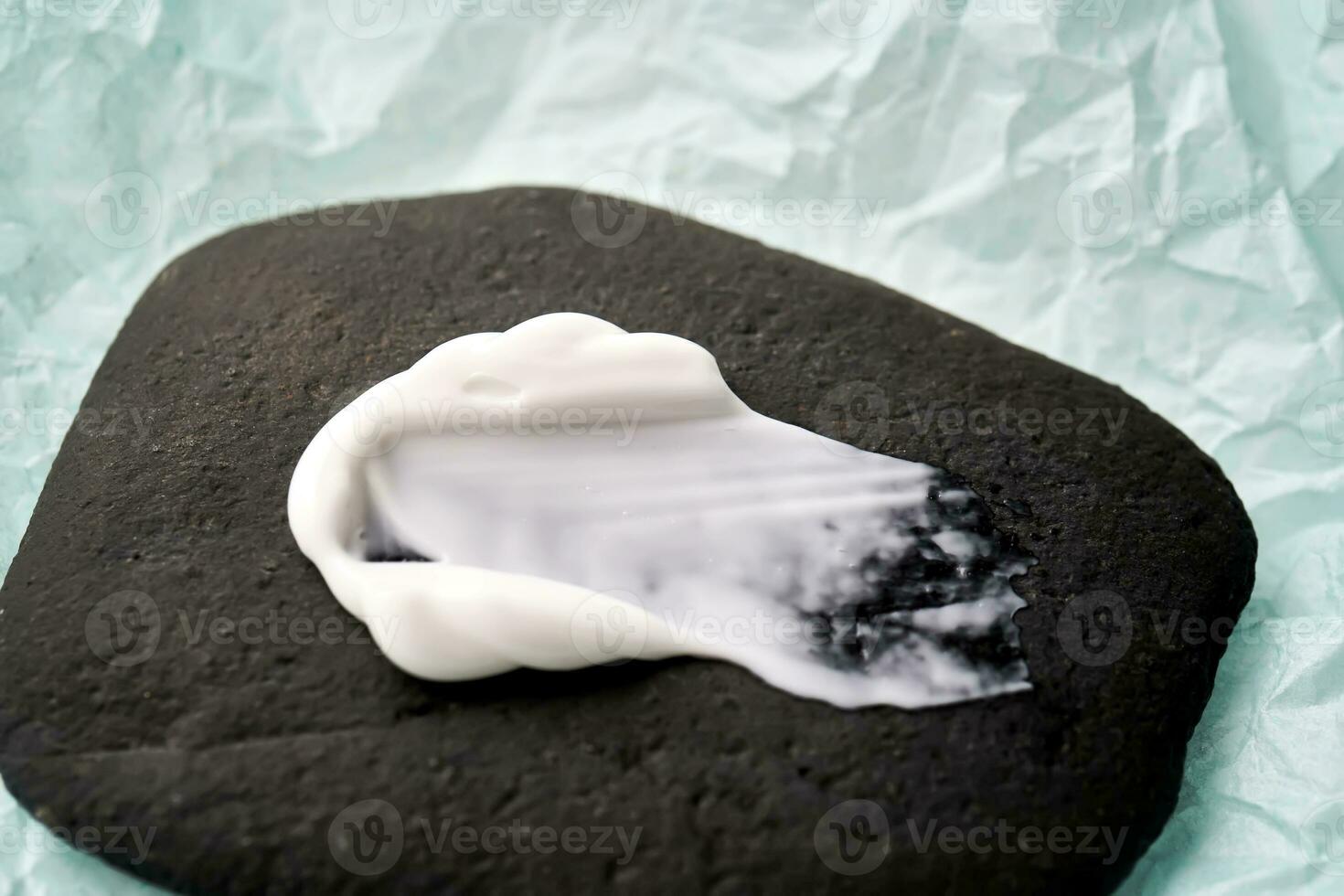 A smear of white cream on a black stone. photo