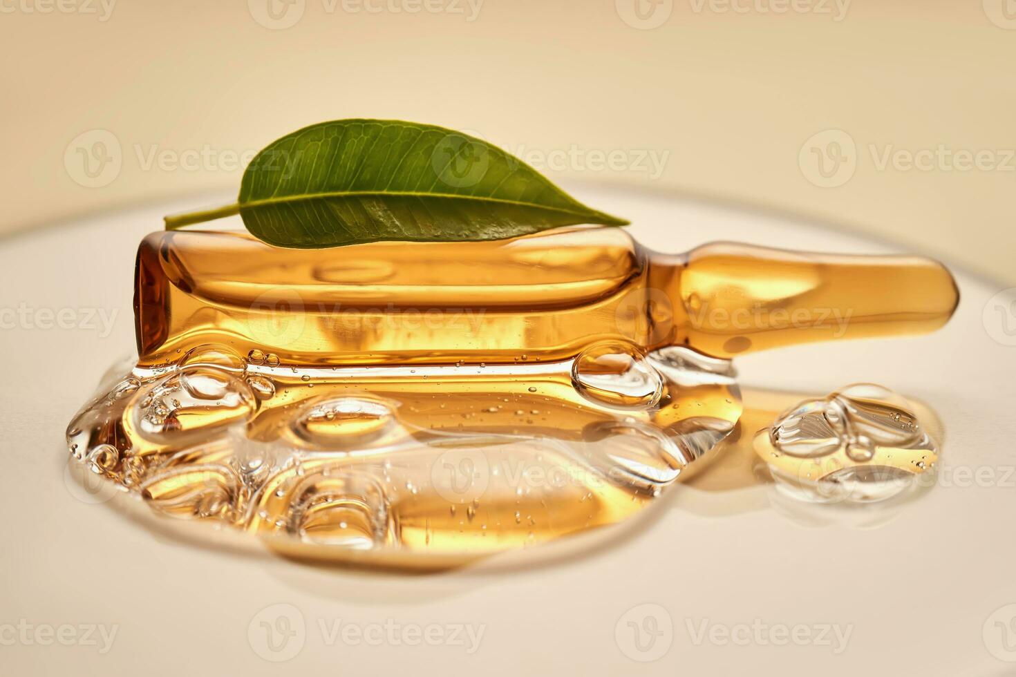 Ampoule in a drop of cosmetic gel on a beige background. photo