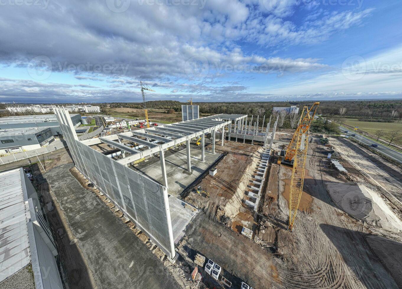 Drone image of a construction site of an industrial building with columns and beams and a heavy-duty crane photo