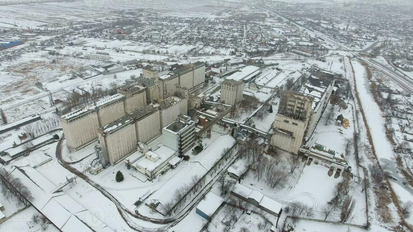 Grain terminal in the winter season. Snow-covered grain elevator in rural areas. A building for drying and storing grain. photo