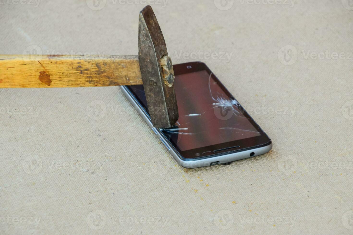 Hammer and smartphone. The screen of the smartphone, a broken ha photo