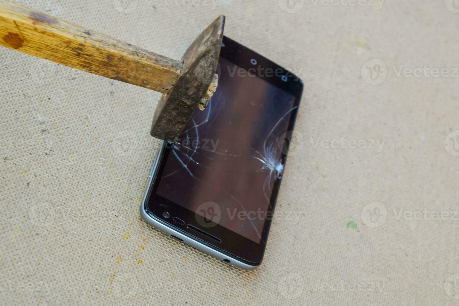 Hammer and smartphone. The screen of the smartphone, a broken ha photo