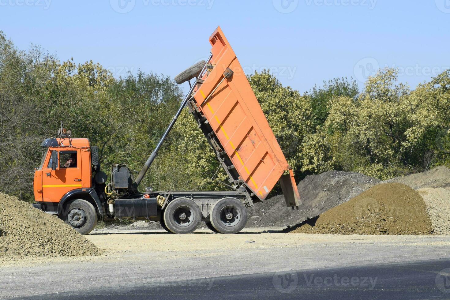 The dump truck unloads rubble. The truck dumped the cargo. Sand and gravel. Construction of roads photo