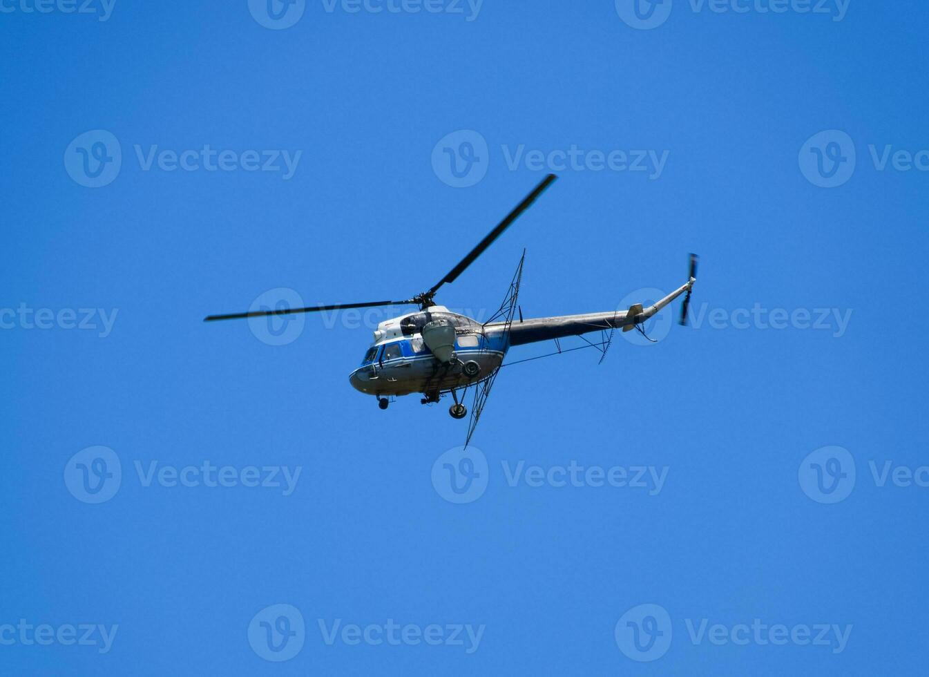 A helicopter of agricultural aviation is flying in the blue sky. photo