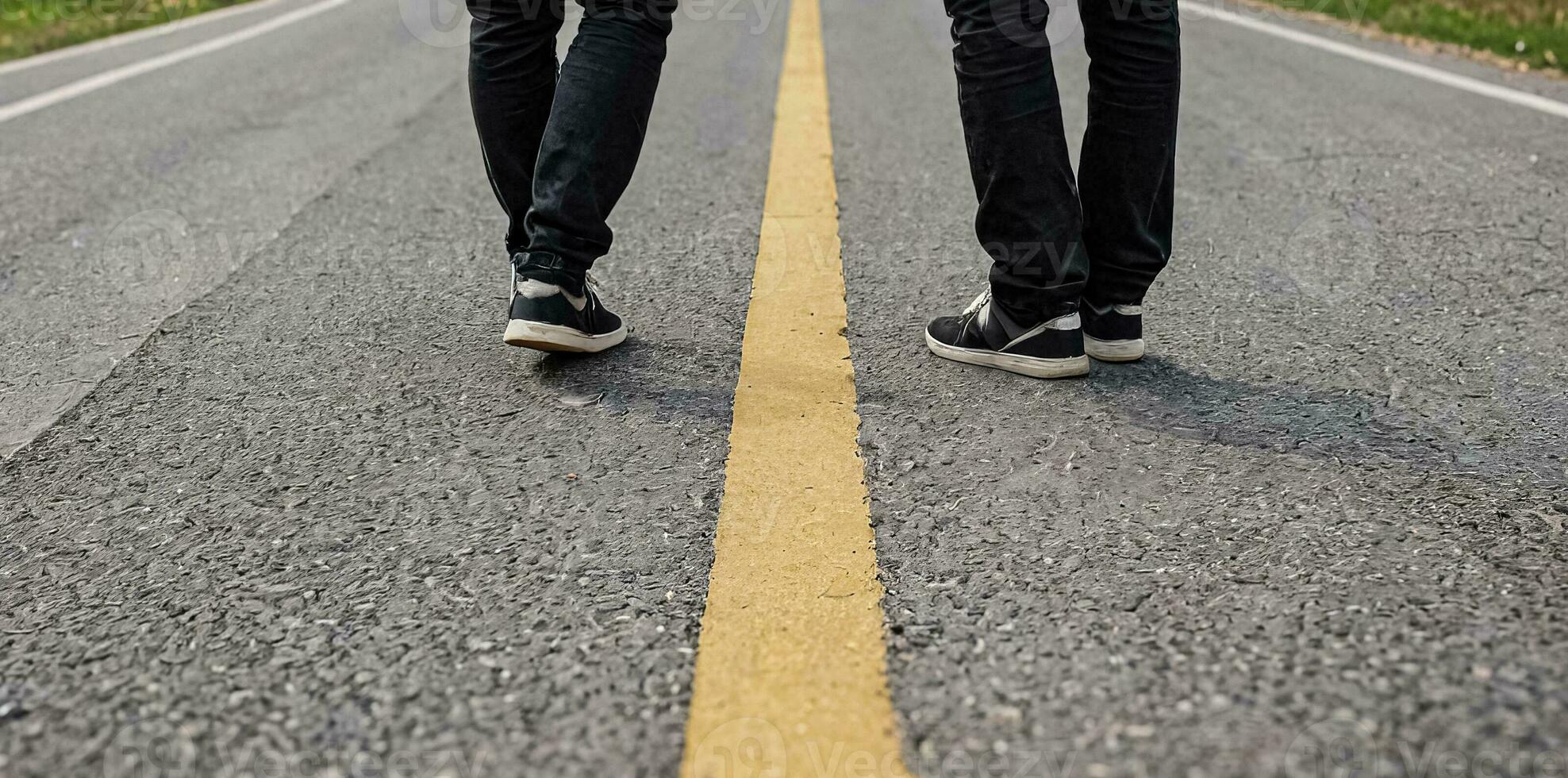 AI generated Two men stand on a road with a yellow median, only the lower parts of their bodies are visible. photo