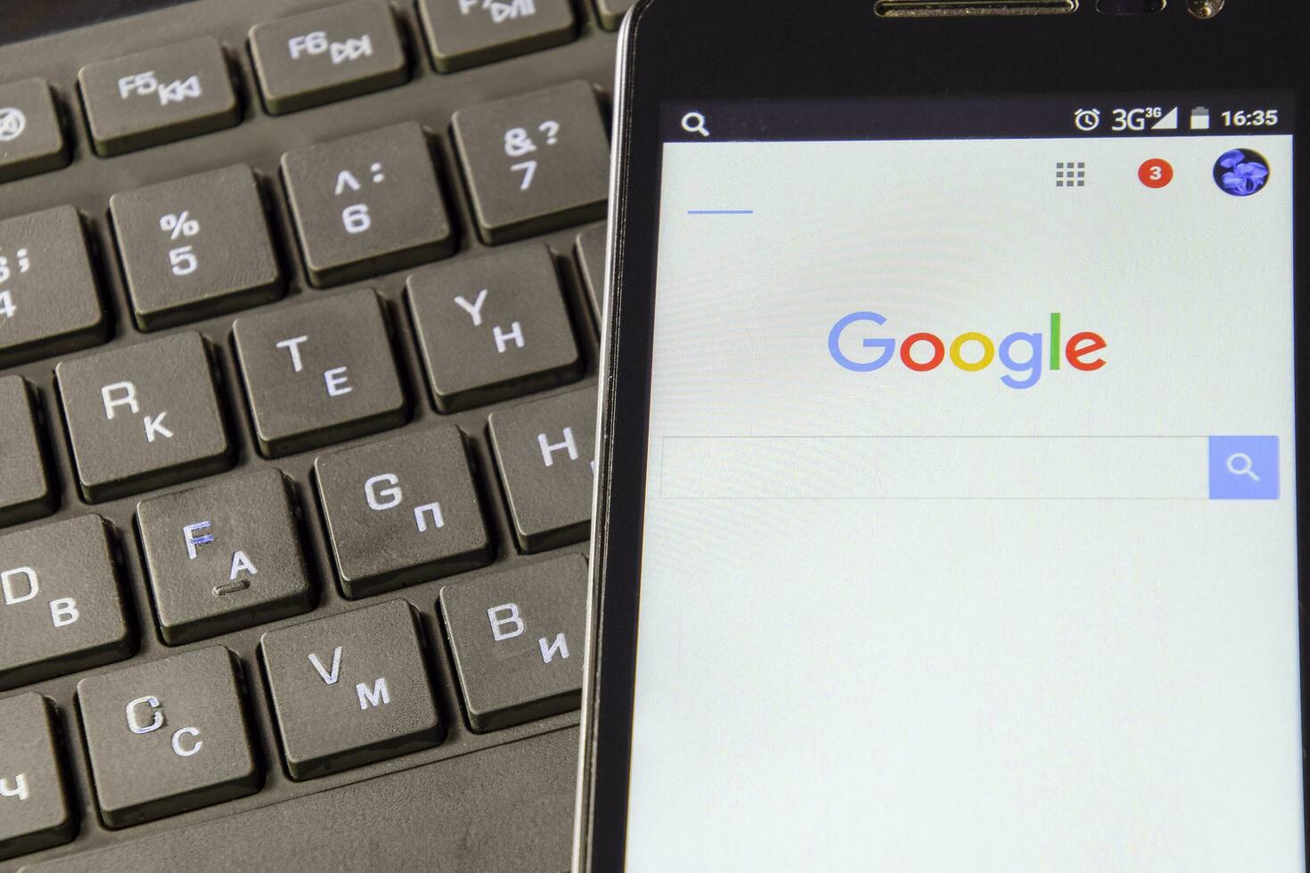 Smartphone with Google search system on the keyboard background. Finding information with the help of Google. photo
