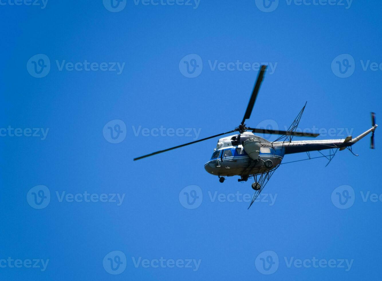 A helicopter of agricultural aviation is flying in the blue sky. photo