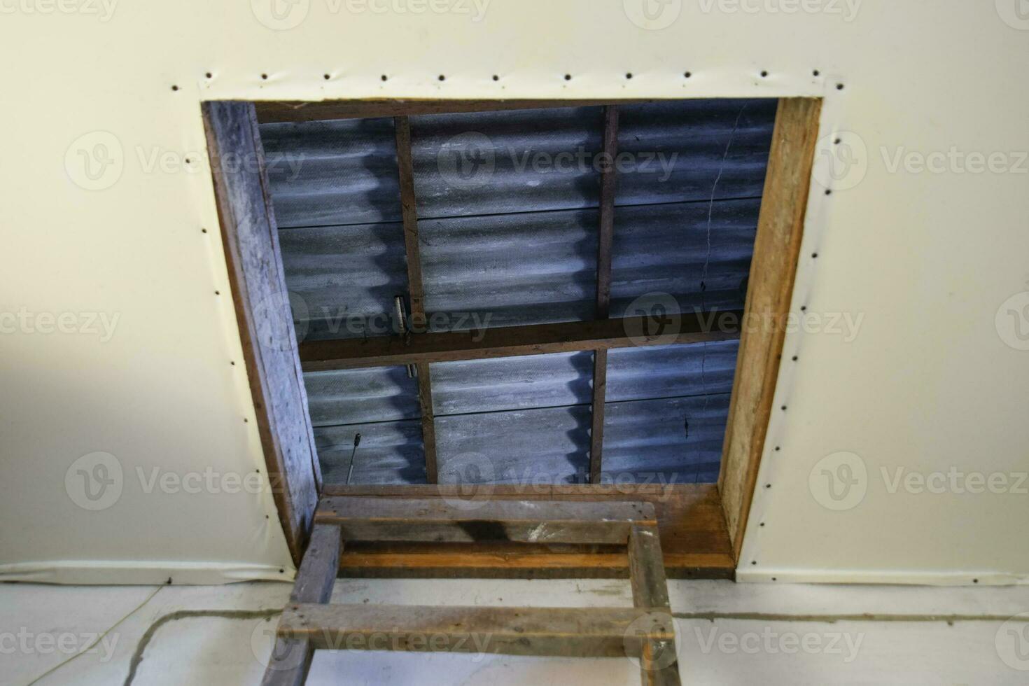 Open the entrance to the attic. The staircase and the door to the attic of the house photo