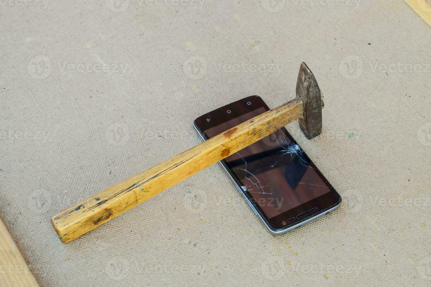 Hammer and smartphone. The screen of the smartphone, a broken ha photo