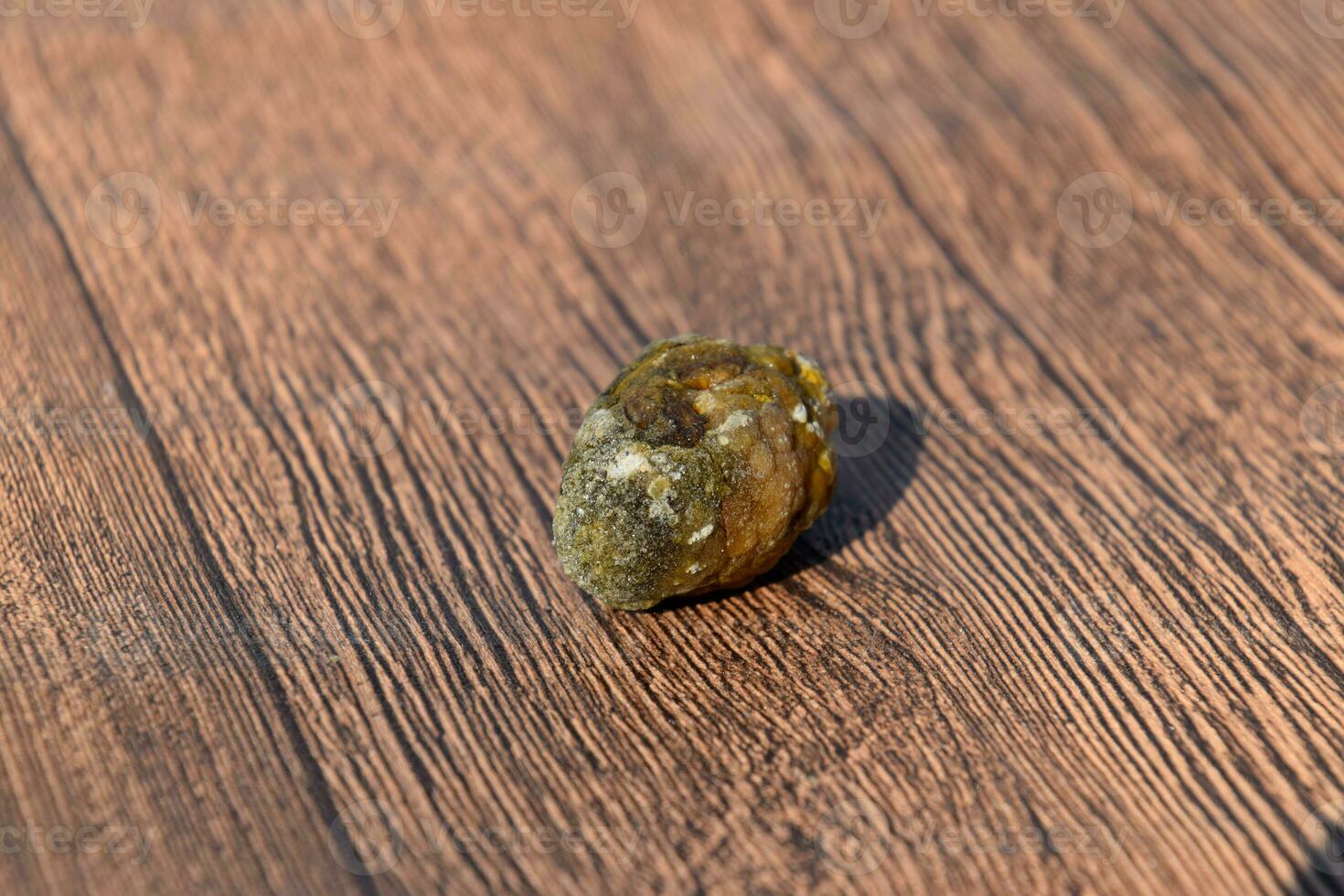 Stone of gallbladder. The result of gallstones. A calculus of dissimilar composition on a wooden background. photo