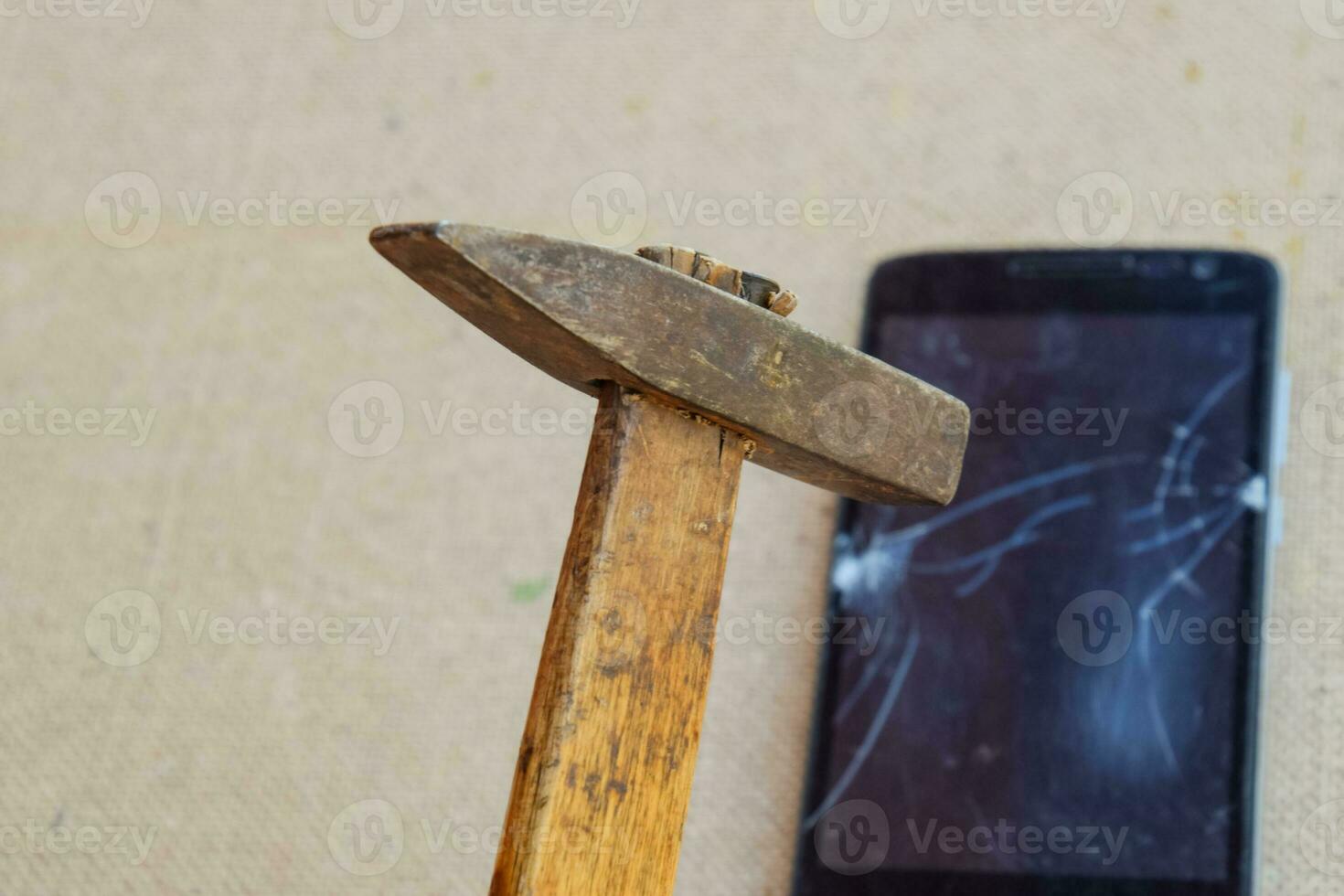 Hammer and smartphone. The screen of the smartphone, a broken ha photo