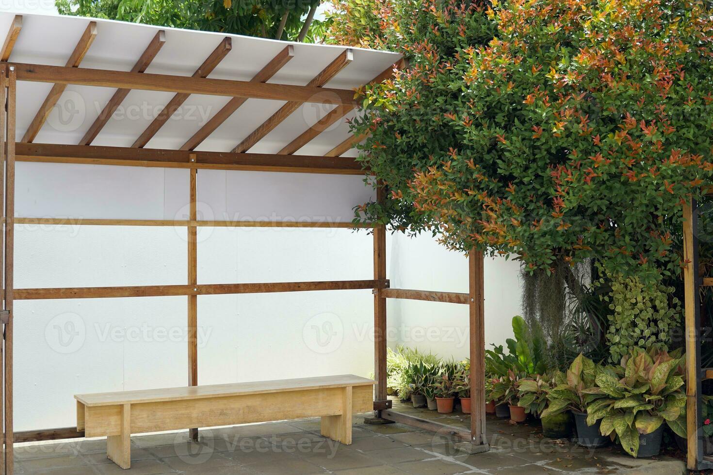 A model of a Japanese bus waiting seat.it is a photo corner at a Japanese-style coffee shop. The surrounding area is decorated with many types of ornamental plants. Soft and selective focus.