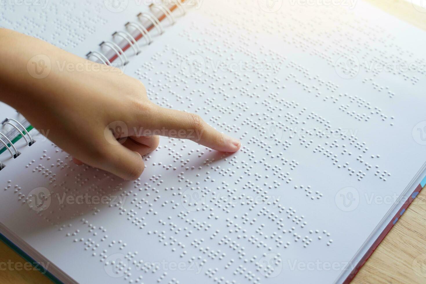 Visually impaired person reads with his fingers a book written in braille It is written for those who are visually impaired or blind. It is a special code generated from 6 dots in the box. photo