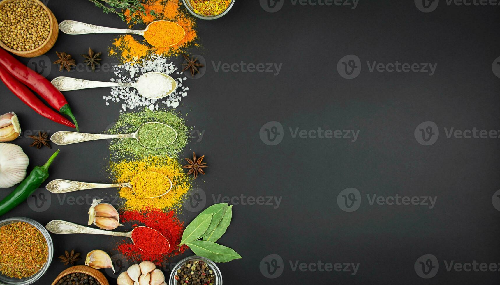 Various spices and herbs in spoons on a dark table. Indian cuisine. Food background. Banner. Copy space. photo