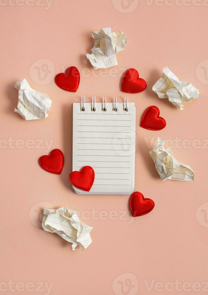 Notebook with hearts and crumpled letters with drafts on a light background. Valentine concept. Confession of love. Flat lay, top view. Copy space. photo