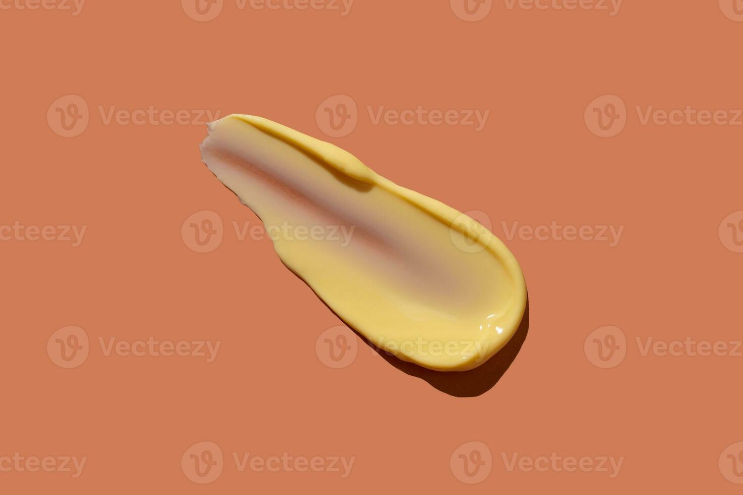 Yellow cosmetic smear of cream texture on a coral background. Skin care. Copy space. photo