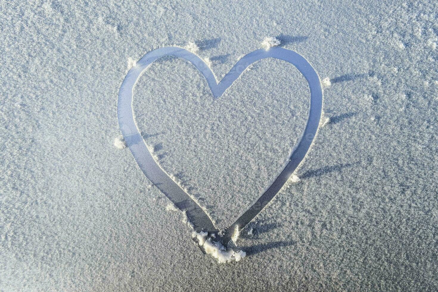 heart drawn in the frost on the hood of the car photo