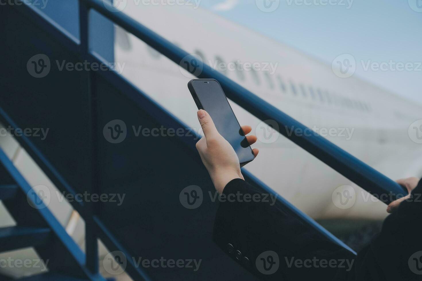 Young asian woman in international airport, using mobile smartphone and checking flight at the flight information board photo