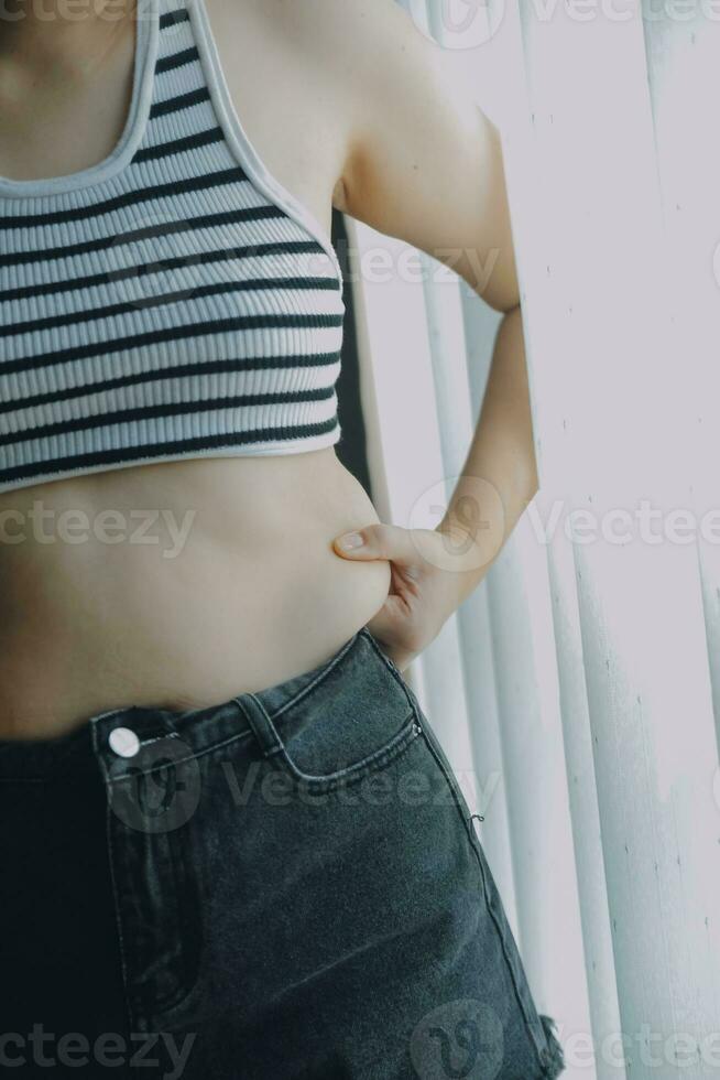 mujer cuerpo grasa barriga. obeso mujer mano participación excesivo barriga gordo. dieta estilo de vida concepto a reducir barriga y forma arriba sano estómago músculo. foto