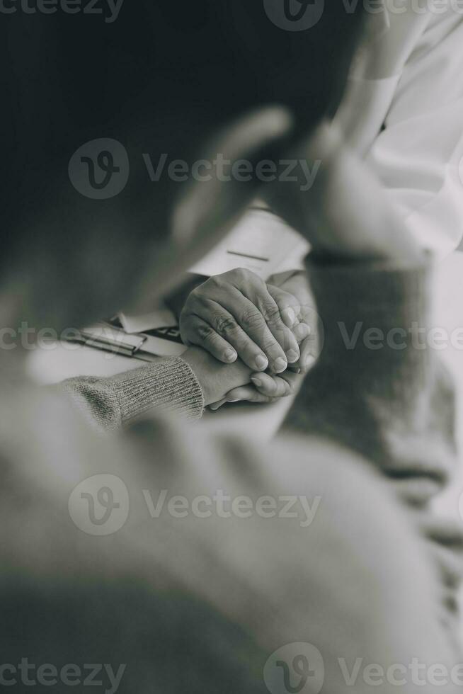 Doctor and patient sitting near each other at the table in clinic office. The focus is on female physician's hands reassuring woman, only hands, close up. Medicine concept photo