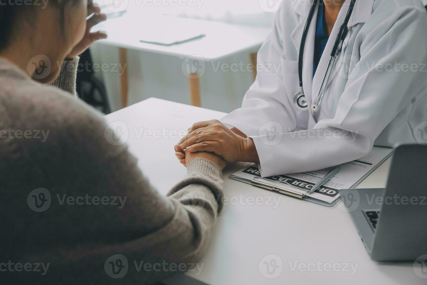 médico y paciente sentado cerca cada otro a el mesa en clínica oficina. el atención es en hembra médico manos tranquilizador mujer, solamente manos, cerca arriba. medicina concepto foto