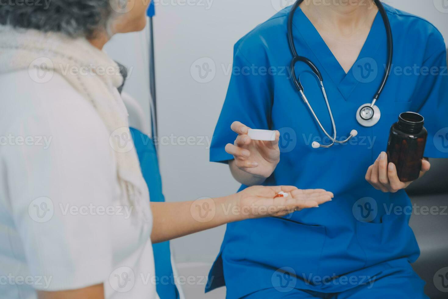Asian woman nurse holding a medicine bottle and telling information to Asian senior woman before administering medication. Caregiver visit at home. Home health care and nursing home concept. photo