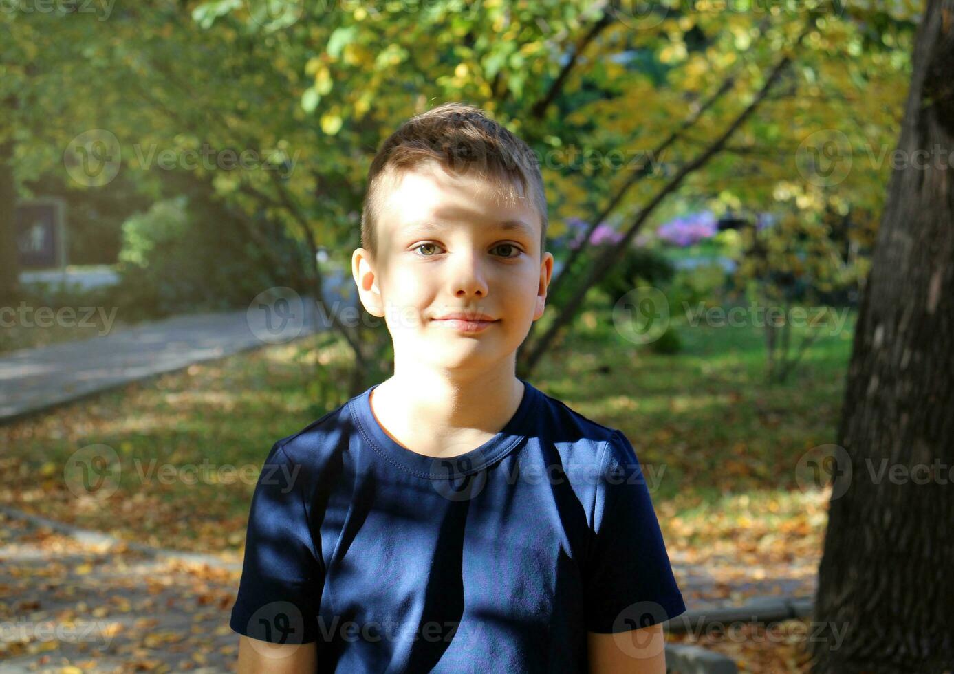 Portrait of a 9 year old blond boy in an autumn park. Handsome caucasian boy with big eyes looks into the camera. photo