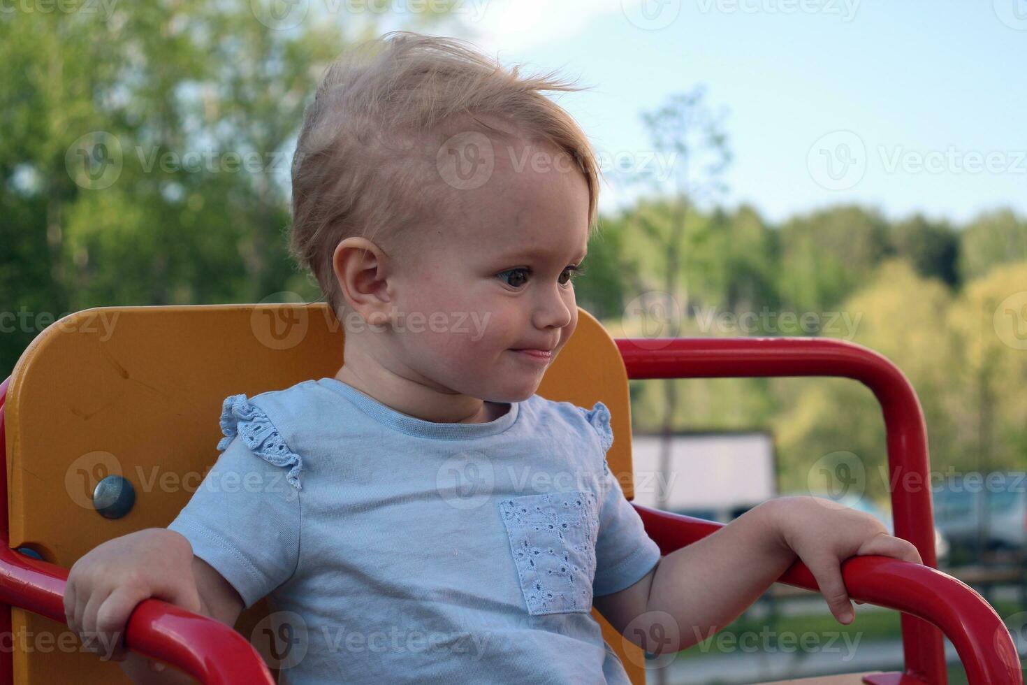 un pequeño niña se sienta en un columpio y sonrisas de cerca retrato. foto