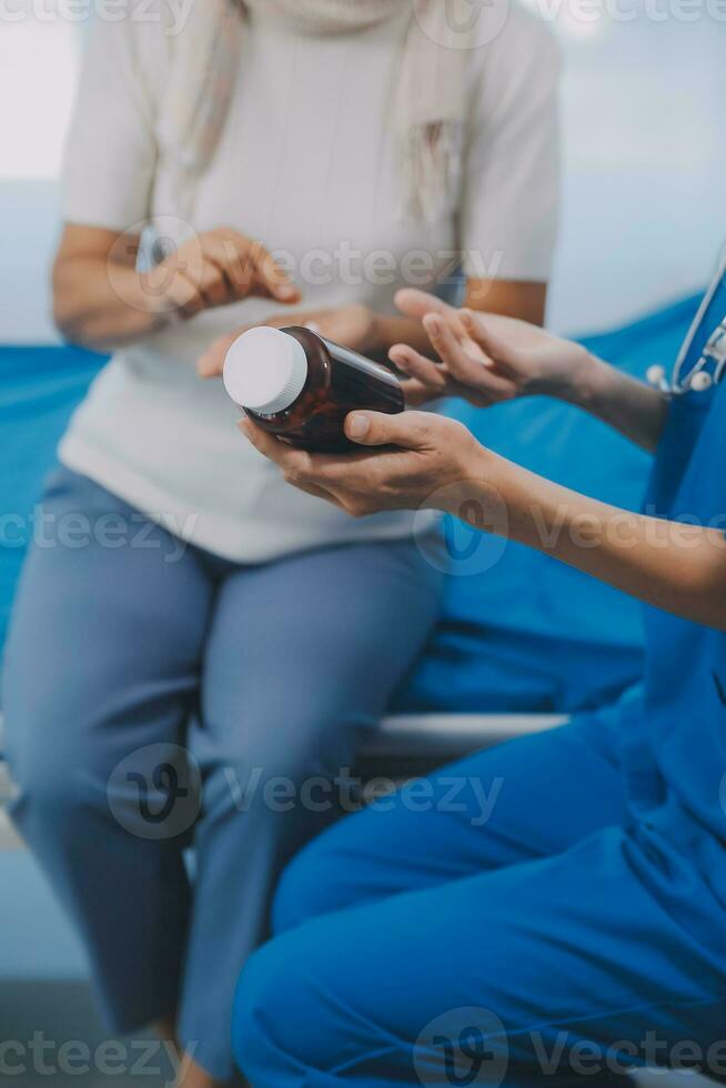 Asian woman nurse holding a medicine bottle and telling information to Asian senior woman before administering medication. Caregiver visit at home. Home health care and nursing home concept. photo