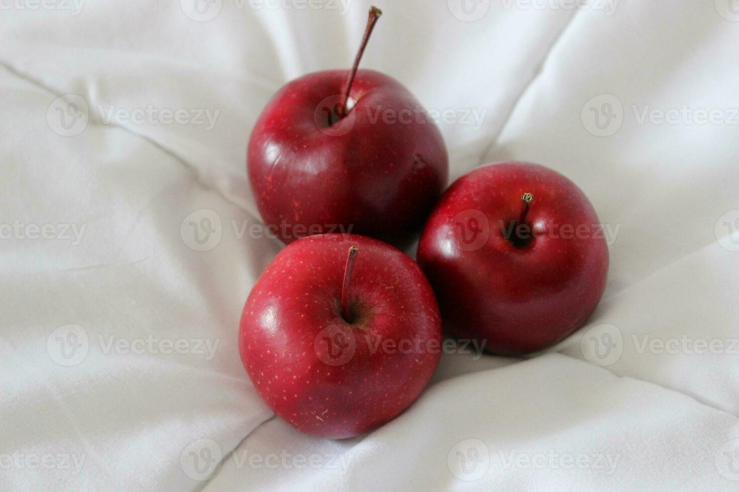 Three fresh red apples on a clean white blanket stock photo for backgrounds