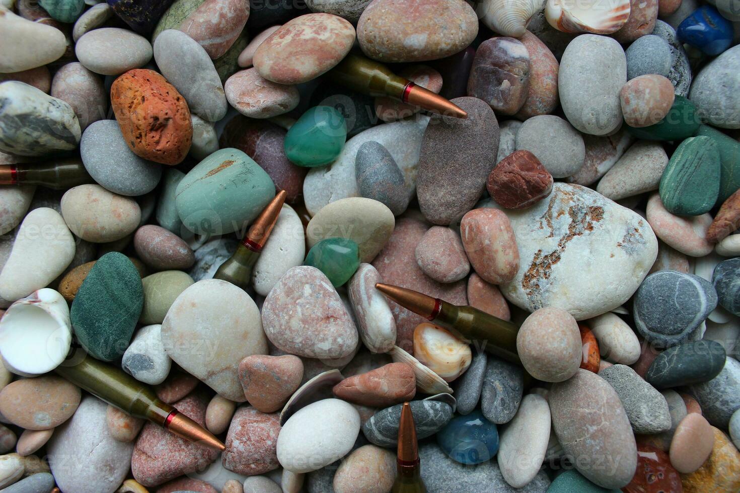 Bullets For a Gun Under Smooth Colored Stones And Seashells Texture Backgrounds photo