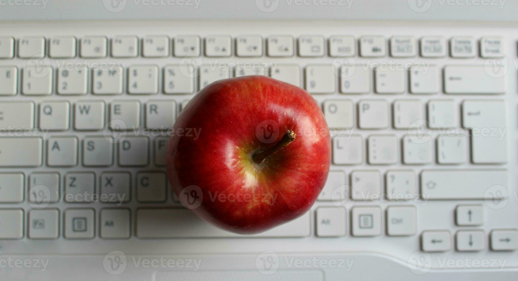 Apple Of Knowledge Concept. Perfect Ripe Apple Fruit On White Defocused Laptop Keyboard Top View photo