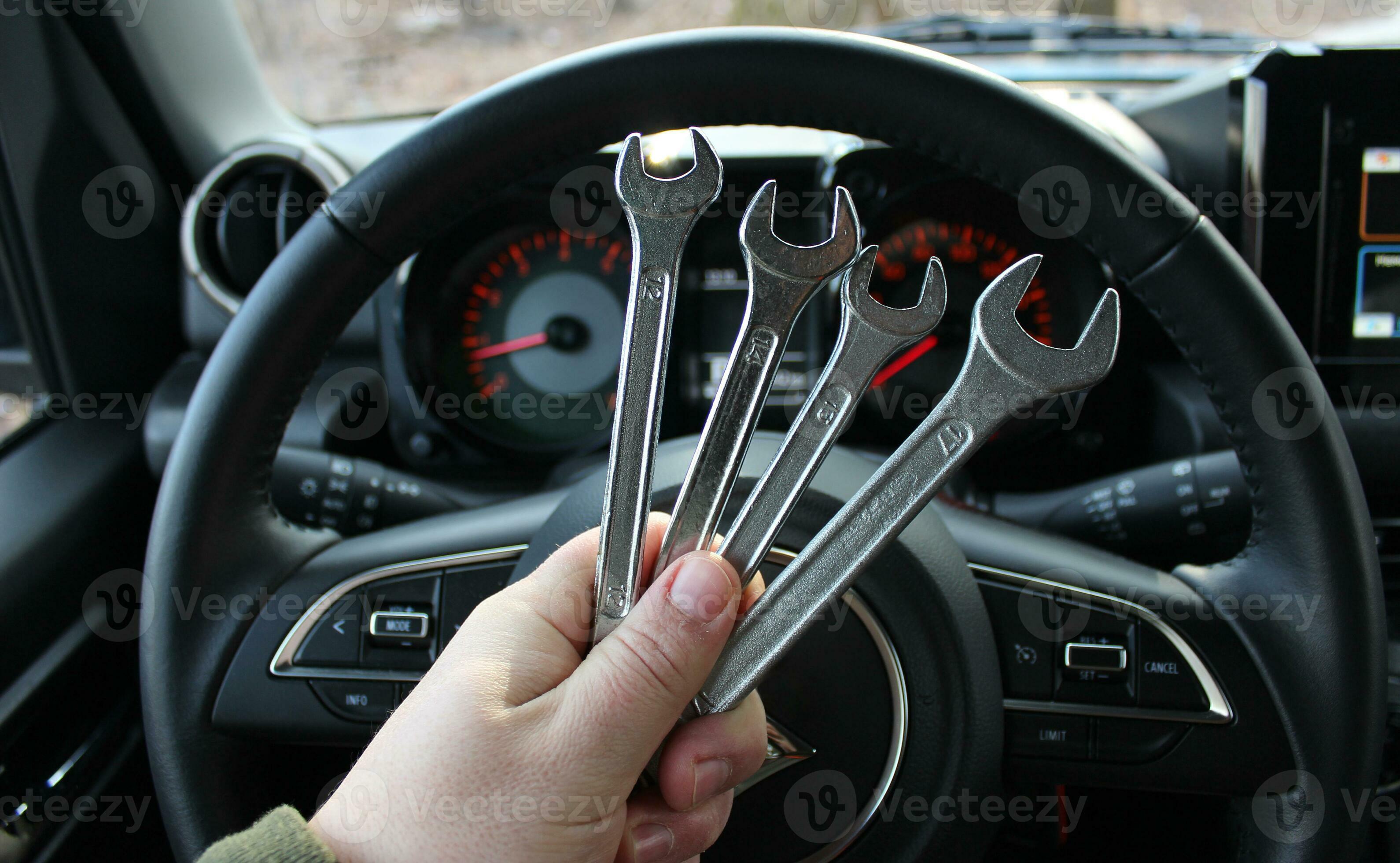 A mechanic holds a bunch of variety diameter wrenches in front of the