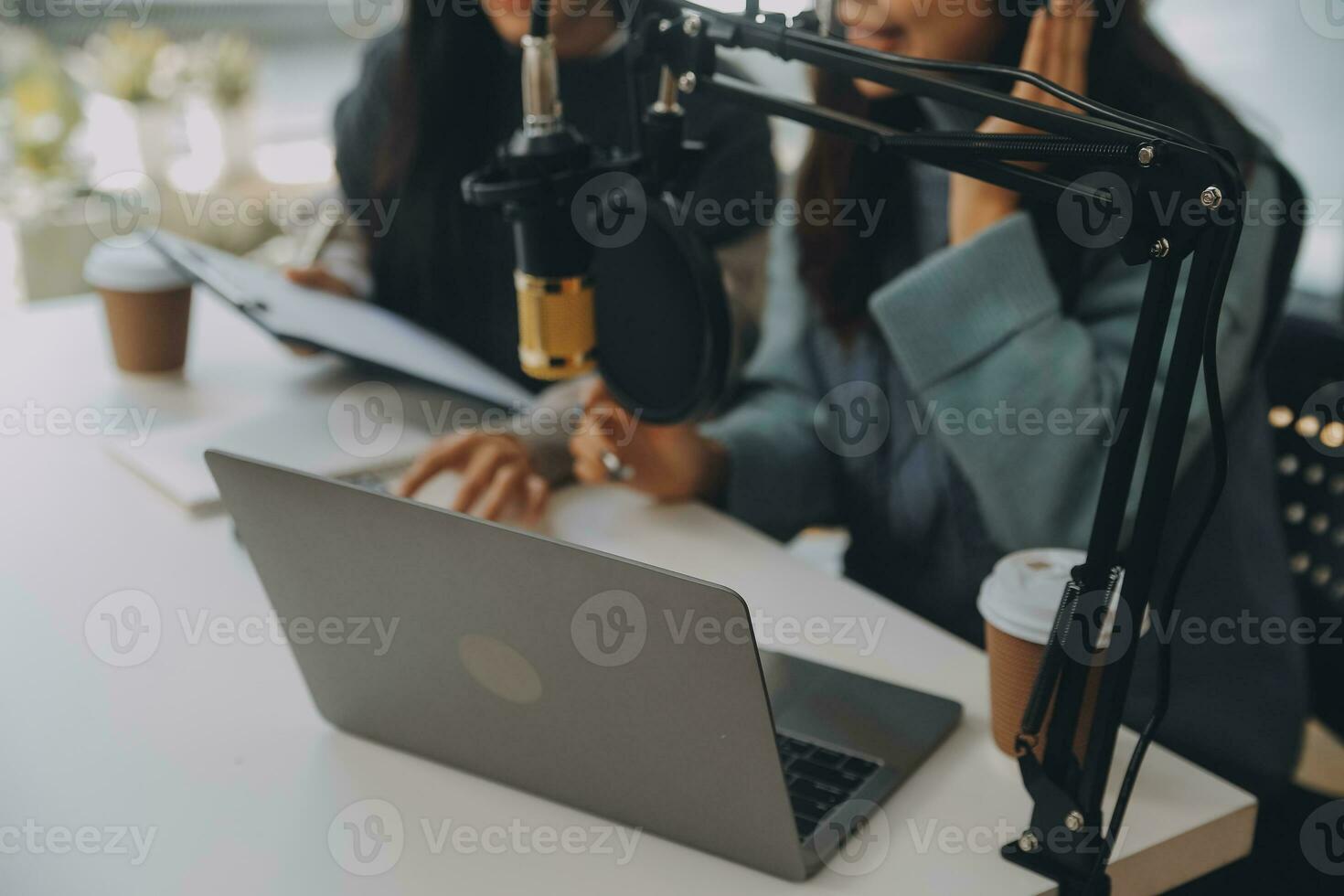 Woman recording a podcast on her laptop computer with headphones and a microscope. Female podcaster making audio podcast from her home studio. photo