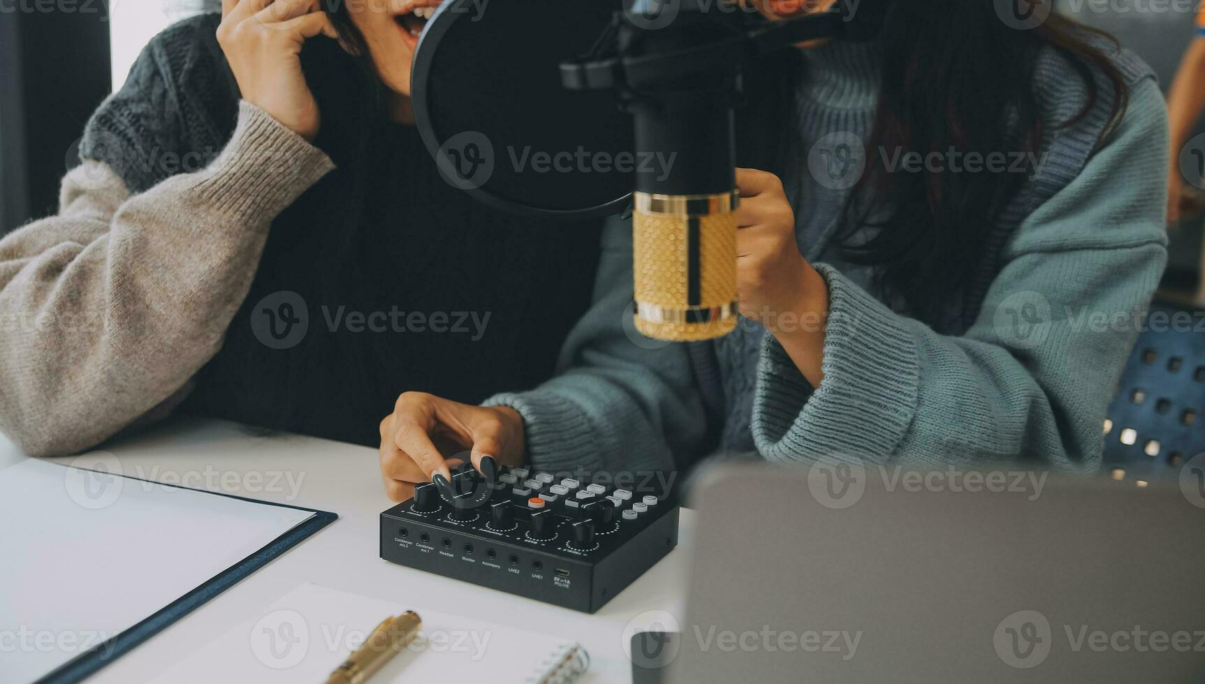 Woman recording a podcast on her laptop computer with headphones and a microscope. Female podcaster making audio podcast from her home studio. photo