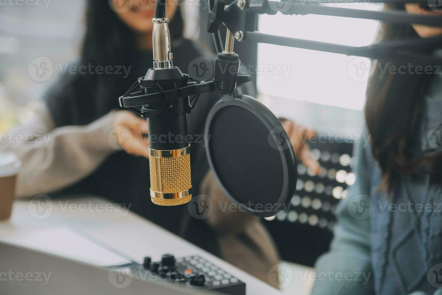Woman recording a podcast on her laptop computer with headphones and a microscope. Female podcaster making audio podcast from her home studio. photo
