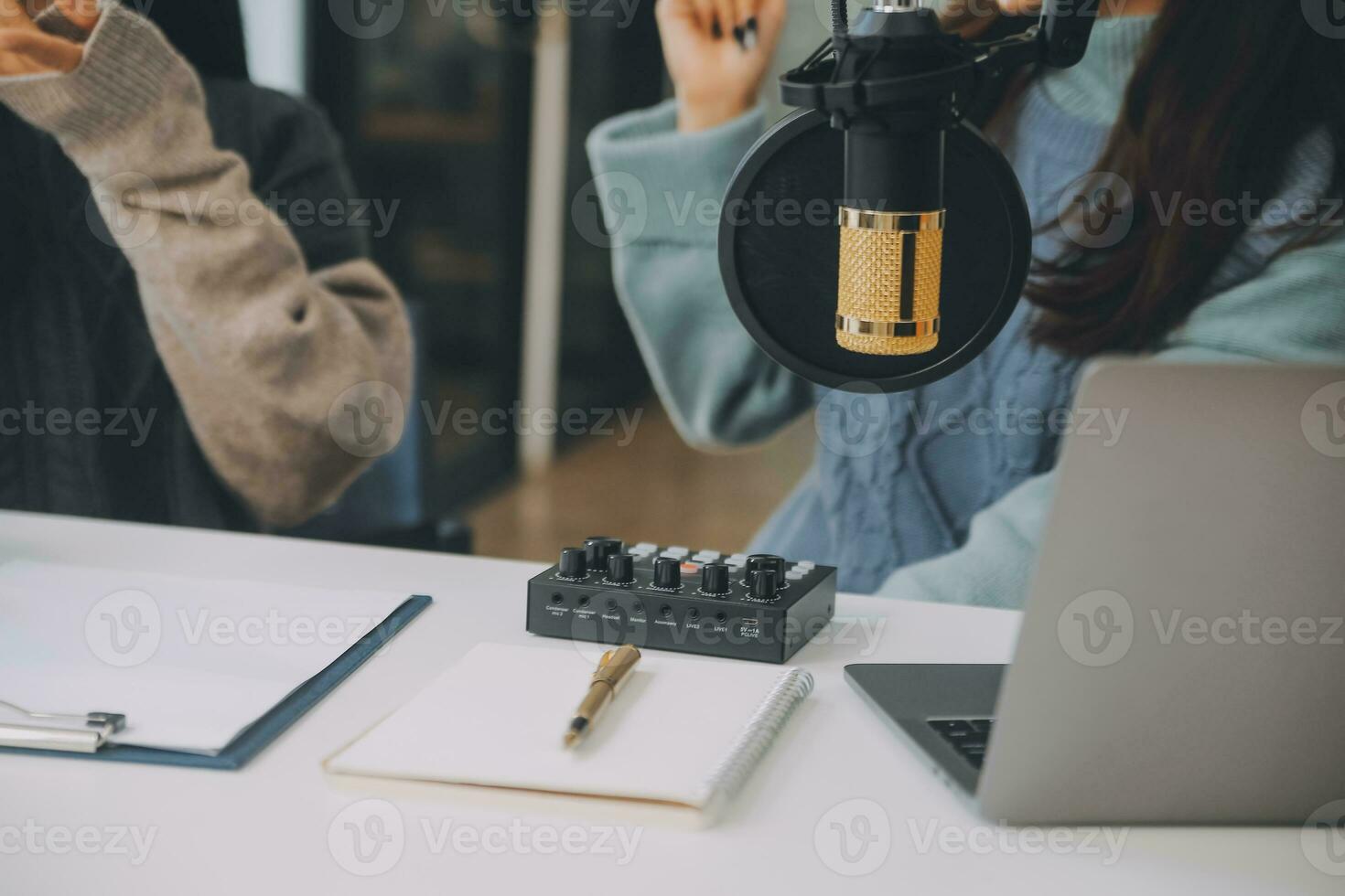 Woman recording a podcast on her laptop computer with headphones and a microscope. Female podcaster making audio podcast from her home studio. photo