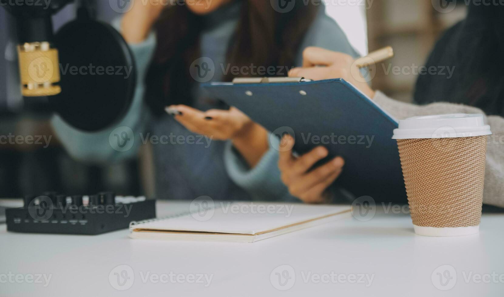 Woman recording a podcast on her laptop computer with headphones and a microscope. Female podcaster making audio podcast from her home studio. photo
