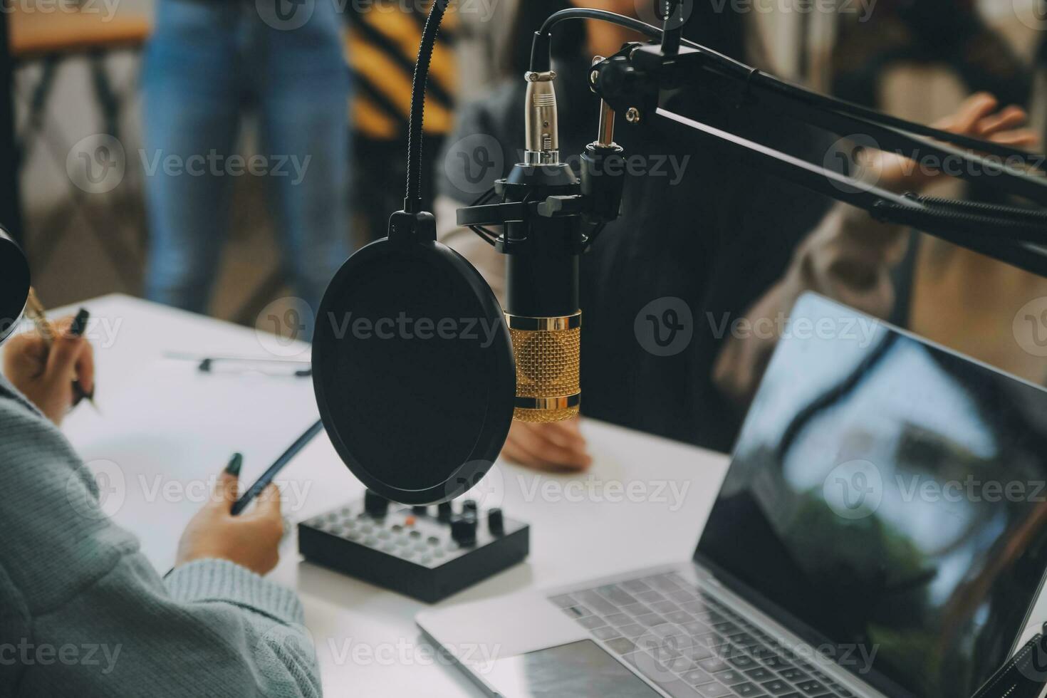 Woman recording a podcast on her laptop computer with headphones and a microscope. Female podcaster making audio podcast from her home studio. photo