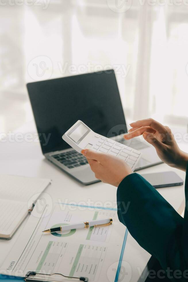 Businessman using a calculator to calculate numbers on a company's financial documents, he is analyzing historical financial data to plan how to grow the company. Financial concept. photo