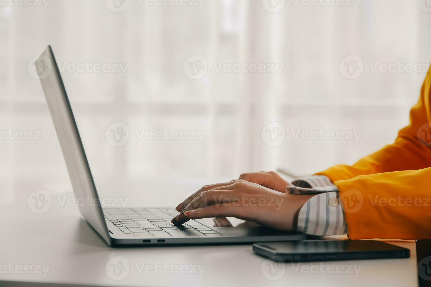 Business woman using mobile phone during working on laptop computer, surfing the internet, searching business data at modern office. Asian businesswoman online working on computer at workplace photo