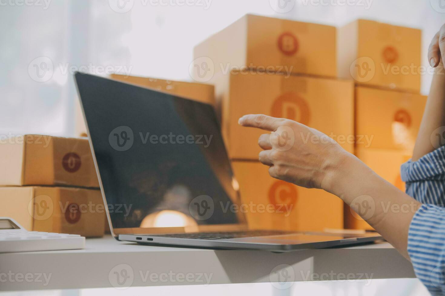 Startup small business entrepreneur or freelance Asian woman using a laptop with box, Young success Asian woman with her hand lift up, online marketing packaging box and delivery, SME concept. photo