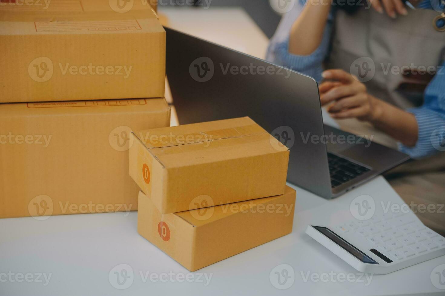 Startup small business entrepreneur or freelance Asian woman using a laptop with box, Young success Asian woman with her hand lift up, online marketing packaging box and delivery, SME concept. photo