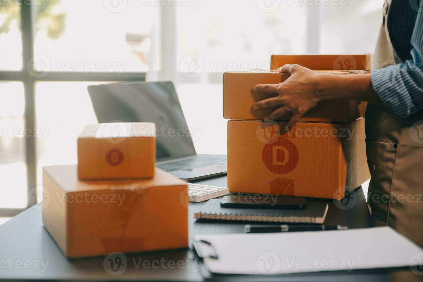 Startup small business entrepreneur or freelance Asian woman using a laptop with box, Young success Asian woman with her hand lift up, online marketing packaging box and delivery, SME concept. photo