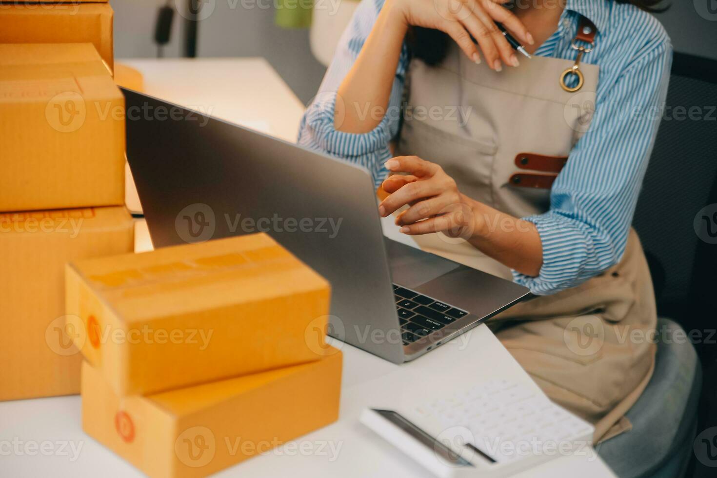 Startup small business entrepreneur or freelance Asian woman using a laptop with box, Young success Asian woman with her hand lift up, online marketing packaging box and delivery, SME concept. photo
