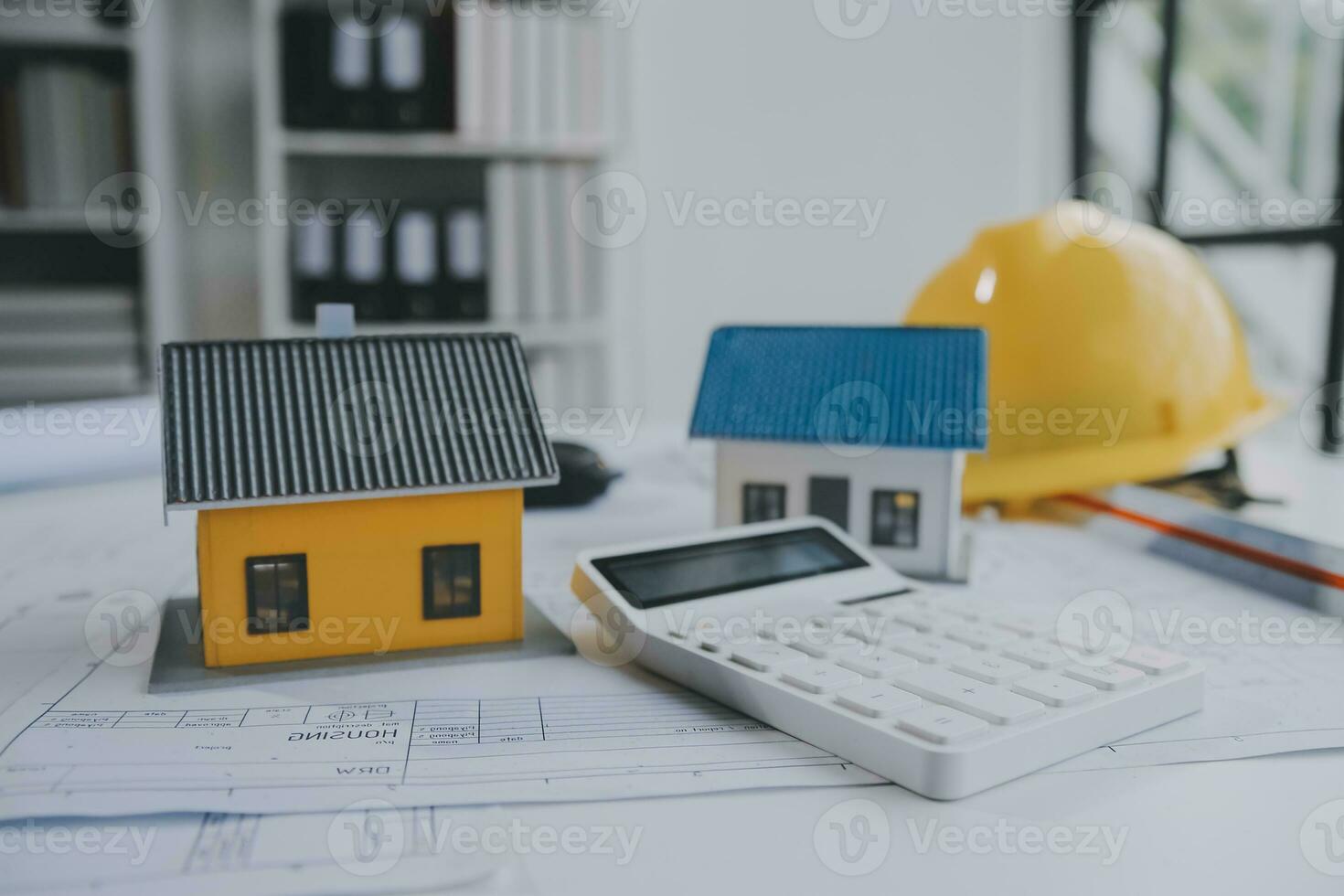 architectural model of houses on desk with drawing technical tools and blueprint rolls, isolated on white background, for building construction plan, interior designer and architect work concept photo
